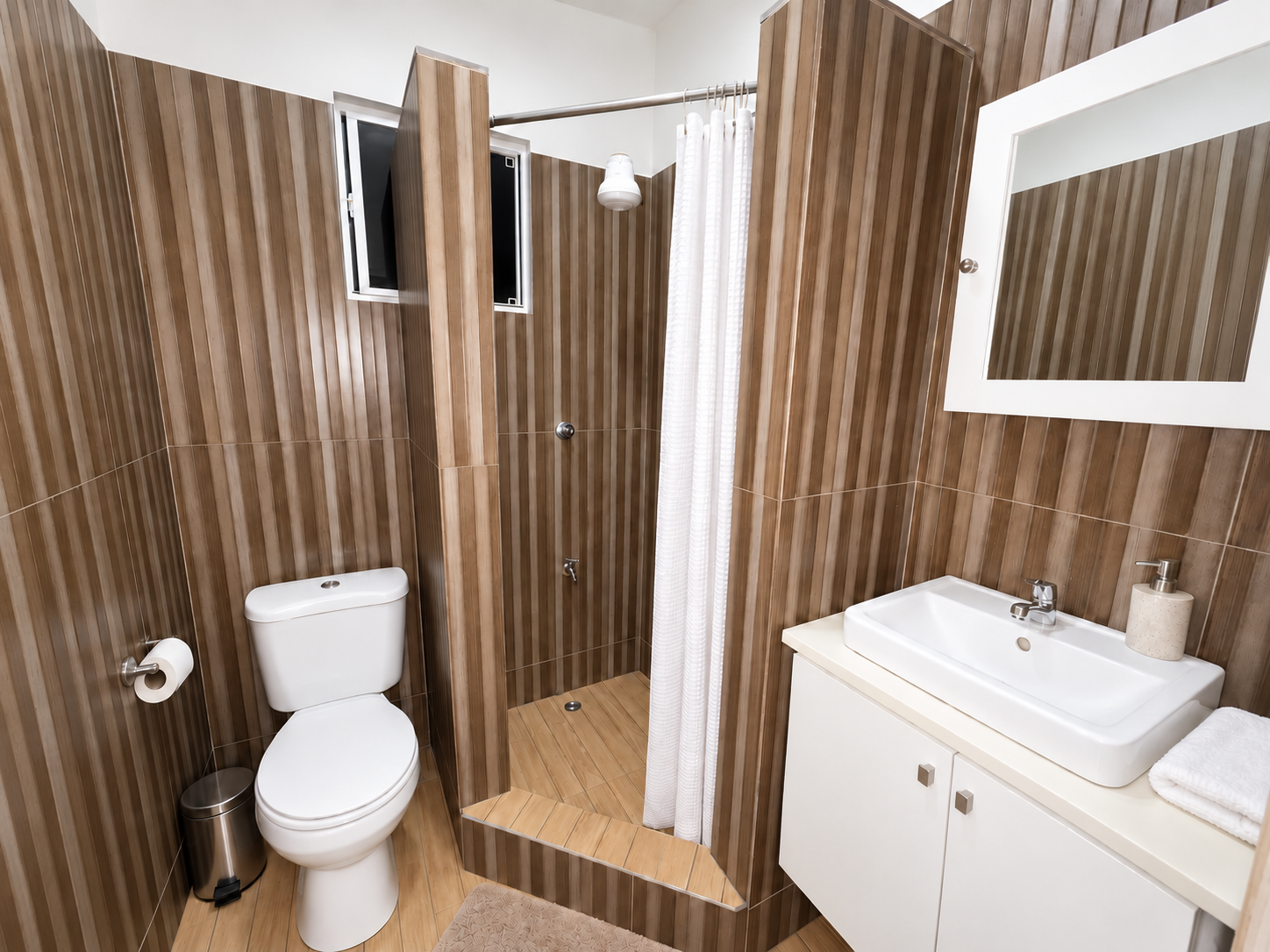 Bathroom with a walk-in shower, a wash basin with mirror above, and wood-effect tiling from floor to ceiling.